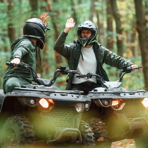 Two people on ATVs high-fiving